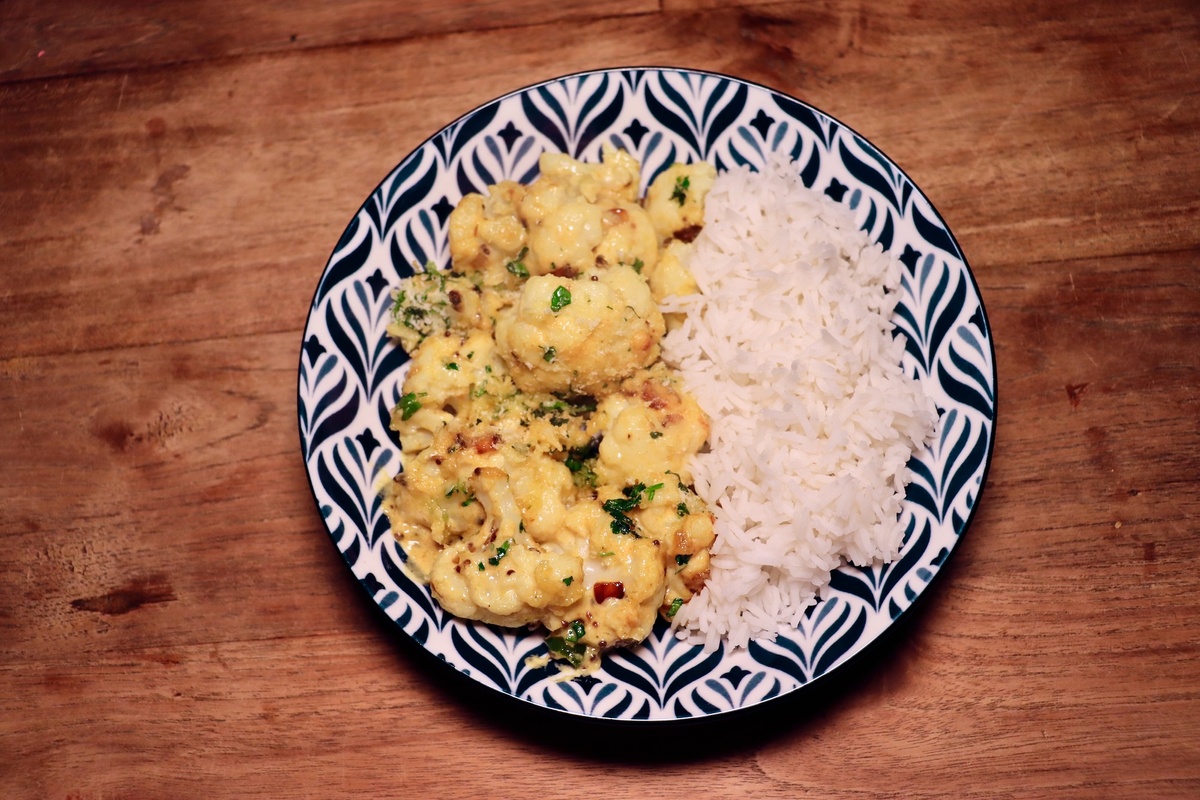 Foto van bloemkool met kaassaus op bord met rijst